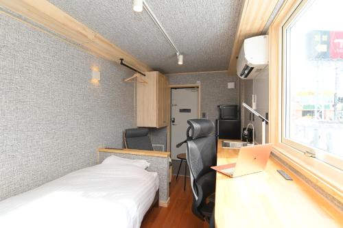 a room with a bed and a desk with a laptop at JR Mobile Inn Chitose in Chitose