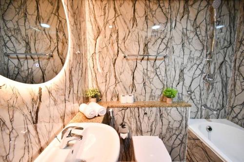 a bathroom with a sink and a mirror and a tub at Heart of DIFC: SKY Gardens Modern Chic Studio in Dubai