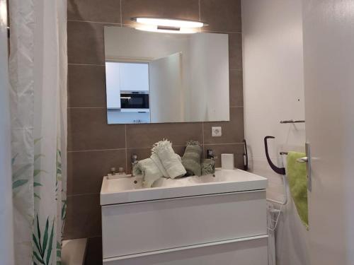 une salle de bain avec un lavabo blanc et un miroir dans l'établissement Studio Le Trident de la mer - Axelle Loc'Appart, à Cannes