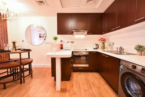 a kitchen with wooden cabinets and a table with a sink at Heart of DIFC: SKY Gardens Modern Chic Studio in Dubai