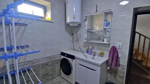een wasruimte met een wasmachine en een raam bij Emir guest house in Batken