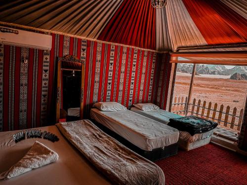 a room with two beds and a window in a tent at RUM YANAL CAMP in Wadi Rum