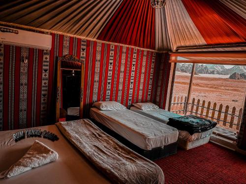 Habitación con 2 camas y ventana en una tienda. en RUM YANAL CAMP en Wadi Rum