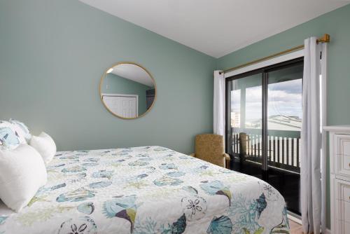 Schlafzimmer mit einem Bett und einem Spiegel sowie einem Balkon in der Unterkunft Sun Catcher Oceanfront Pool Balcony in North Topsail Beach