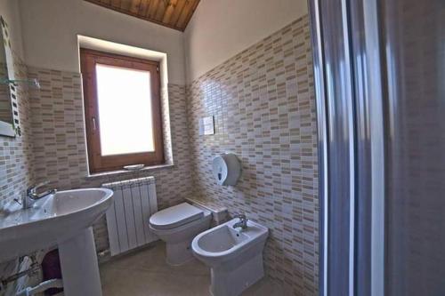 uma casa de banho com um lavatório, um WC e uma janela. em QUERCIA ANTICA em Masseria di Rusciano