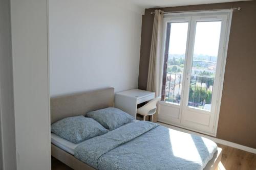 una piccola camera con letto e finestra di Appartement de Charme a Épinay-sur-Seine