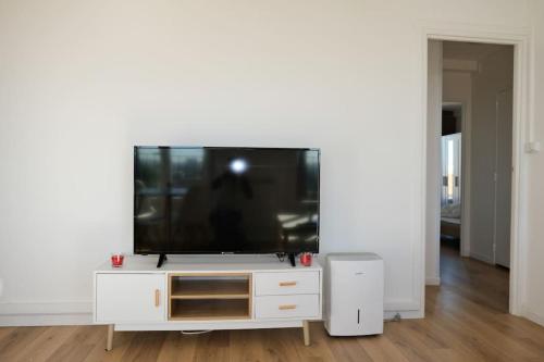 una TV a schermo piatto seduta su un centro di intrattenimento bianco di Appartement de Charme a Épinay-sur-Seine