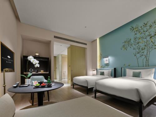 a hotel room with two beds and a table at Maison Albar Hotels Leshan in Leshan