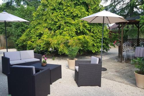 um pátio com 2 cadeiras e um guarda-sol em La Gloriette des Eglantines em Saint-Gervais-la-Forêt