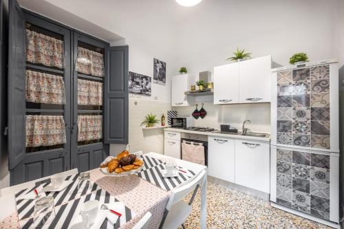 a kitchen with white cabinets and a table with a bowl of fruit at Casa Vacanze TaorminaCentre Guest house in Taormina