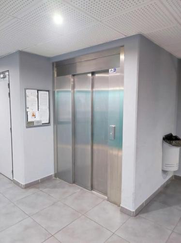un couloir avec deux ascenseurs dans un bâtiment dans l'établissement T1 rénové à Nîmes, à Nîmes