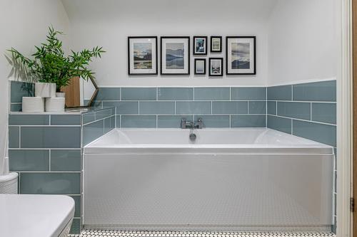 y baño con bañera y azulejos azules. en NR RHOSNEIGR-3 BED-STYLISH-RE-FURBISHED HOLIDAY HOME, en Rhosneigr