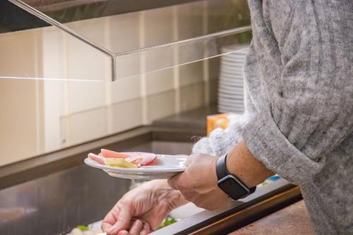 a person holding a plate of food in a kitchen at Hotel - Gasthof Blume in Oppenau