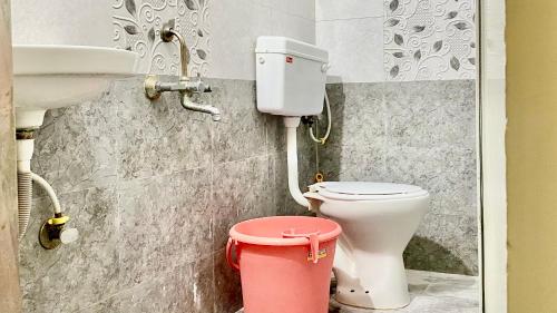 a bathroom with a toilet and a sink and a bucket at Hotel Shree Prabhu in Vovale