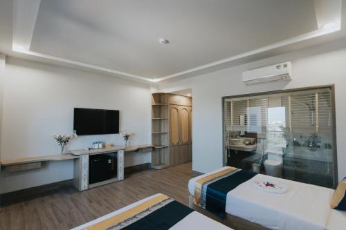 ein Hotelzimmer mit einem Bett und einem Flachbild-TV in der Unterkunft Khoa Hotel Phan Thiết in Ấp Bình Hưng