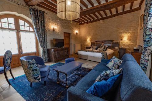 un soggiorno con divano blu e letto di Ferme de la Rançonnière - Hôtel & Restaurant a Crépon