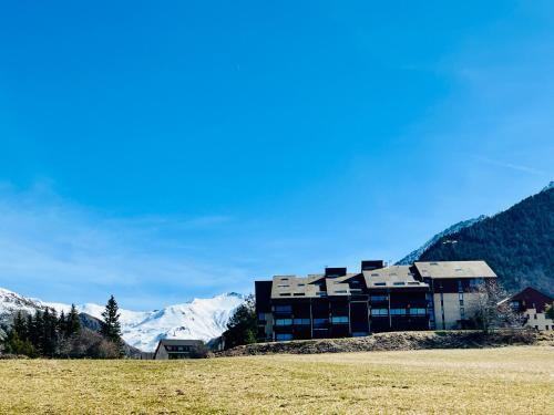 a building in a field with mountains in the background at Le SAPET in Ancelle