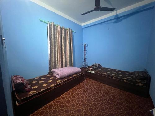 a blue room with two beds and a window at Hotel Atithi Devo Bhava in Lālbhitti