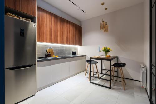 uma cozinha com um frigorífico e uma mesa com bancos em Stylish & Modern Apartment I Blueloft 48 em Tashkent