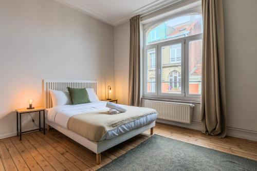 een slaapkamer met een bed en een groot raam bij 2 bedroom apartment with terrace, near Lille in Lille