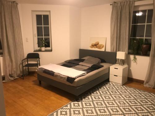 - une chambre avec un lit, une chaise et des fenêtres dans l'établissement Haus im Grünen, à Lippstadt