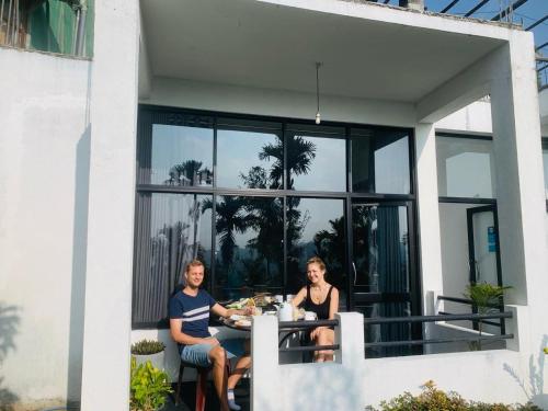 two people sitting at a table on the balcony of a house at Monarch Ella in Ella