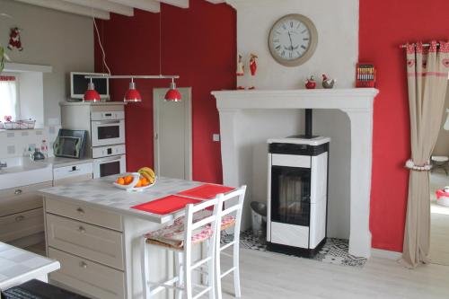 Il comprend une cuisine dotée d'un mur rouge et d'une cheminée. dans l'établissement Chambres à la campagne, à Requeil