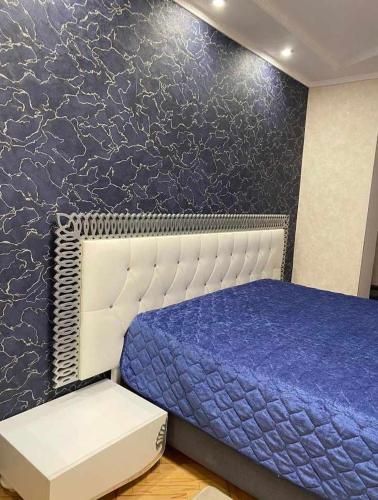 a bedroom with a bed and a blue wall at Dighomi Apartment in Tbilisi City