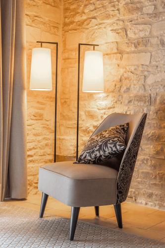 a chair in a room with two lamps on the wall at Ferme de la Rançonnière - Hôtel & Restaurant in Crépon