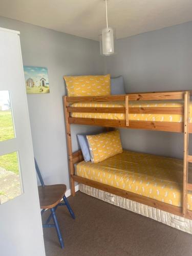 a room with two bunk beds and a chair at Delightful chalet, overlooking estuary! in Ferryside