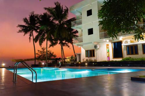 a swimming pool in front of a building with palm trees at Skylar Seaview Beach Resort & Ayurveda Varkala in Varkala