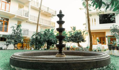 a fountain in the grass in front of a building at Skylar Seaview Beach Resort & Ayurveda Varkala in Varkala