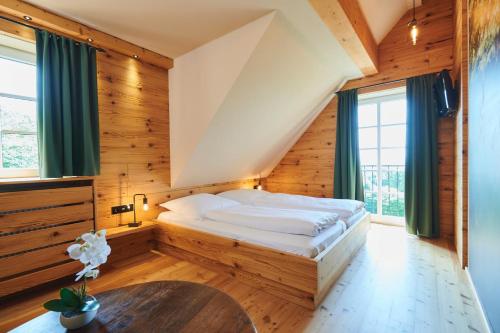 a bed in a room with wooden walls and windows at Hotel Agnesen-Hof in Barweiler