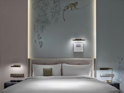 a bedroom with a white bed with a monkey on the wall at Maison Albar Hotels Leshan in Leshan