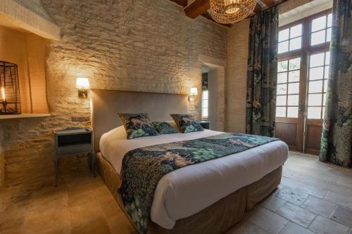 a bedroom with a large bed and a stone wall at Ferme de la Rançonnière - Hôtel & Restaurant in Crépon
