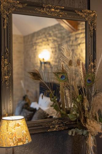 a mirror on a wall with a lamp and a vase at Ferme de la Rançonnière - Hôtel & Restaurant in Crépon
