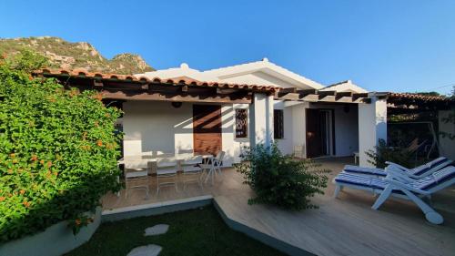 a house with a wooden deck with a table and chairs at Italianflat - Villa Andrea Doria in Costa Rei