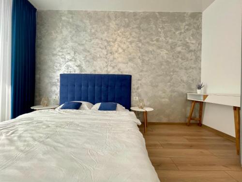 une chambre avec une tête de lit bleue et un lit dans l'établissement Seaside Apartments Mamaia Nord, à Mamaia Nord – Năvodari