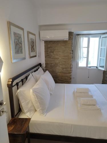 a bedroom with a bed with white sheets and pillows at Korina's Suites in Andros