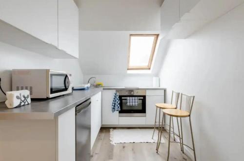 a kitchen with a microwave and some chairs in it at Beautiful fully renovated apartment in Brussels