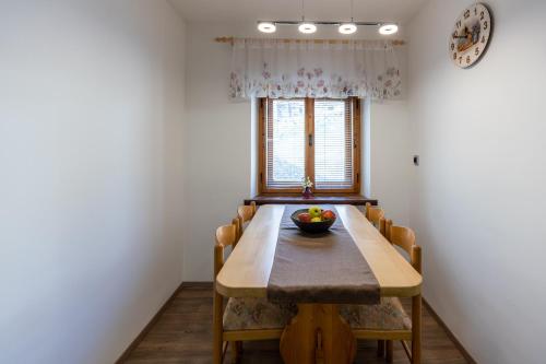 einen Esstisch mit Stühlen und eine Obstschale darauf in der Unterkunft Apartma pri Andreju in Bohinj