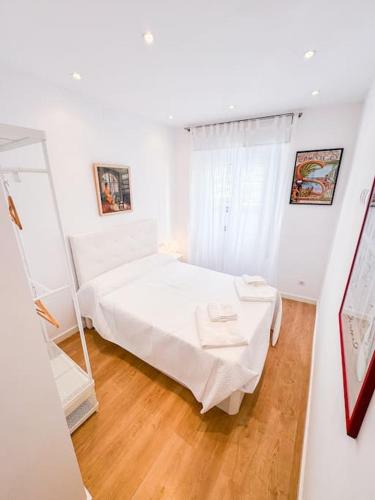 a white bedroom with a bed and a mirror at Anna & Thomas - Sitges Center Apt in Sitges