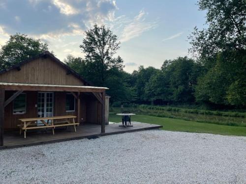 a pavilion with a picnic table and a picnic bench at Chalet et étangs 2 chambres in Henrichemont