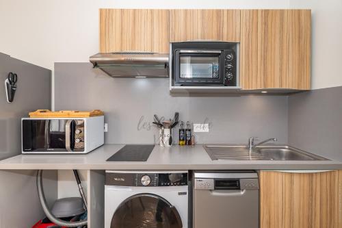 a kitchen with a sink and a microwave and a washing machine at Les Cahiers de Vacances in Amboise