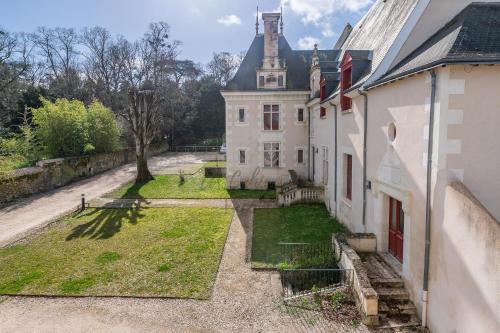 an old house with a grass yard next to a building at Les Cahiers de Vacances in Amboise