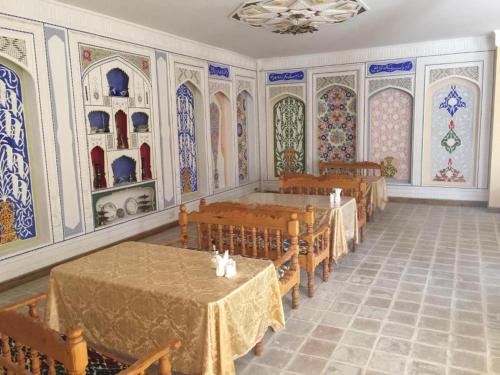 een eetkamer met tafels en stoelen en schilderijen aan de muren bij Zaytoon Guest House in Bukhara