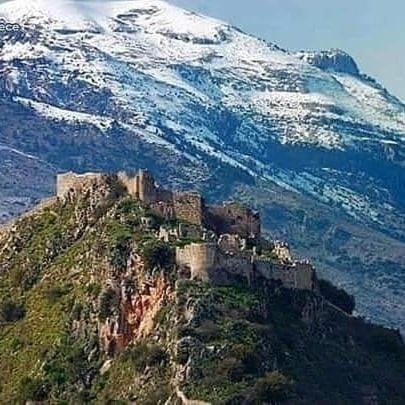 a castle on a mountain in front of a snow covered mountain at HELLAS PALACE ROOMS balcony in Sparti