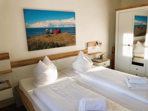 a bedroom with a white bed with a picture on the wall at Feriendorf Rugana - Komfort Appartement mit 1 Schlafzimmer und Terrasse B37 in Dranske