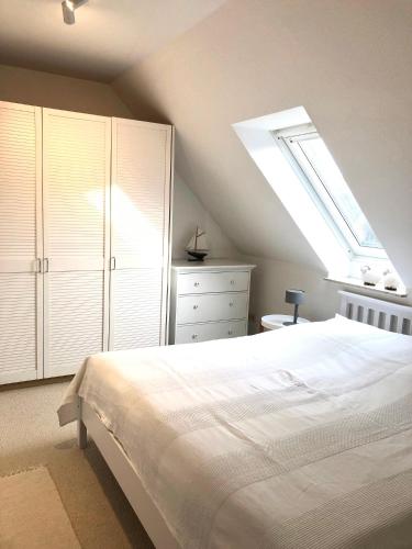a bedroom with a white bed and a skylight at Ferienwohnung am Seezeichen in Böhl