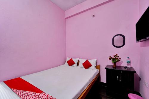 a bedroom with pink walls and a bed and a table at SPOT ON Hotel Gajraj in Patna